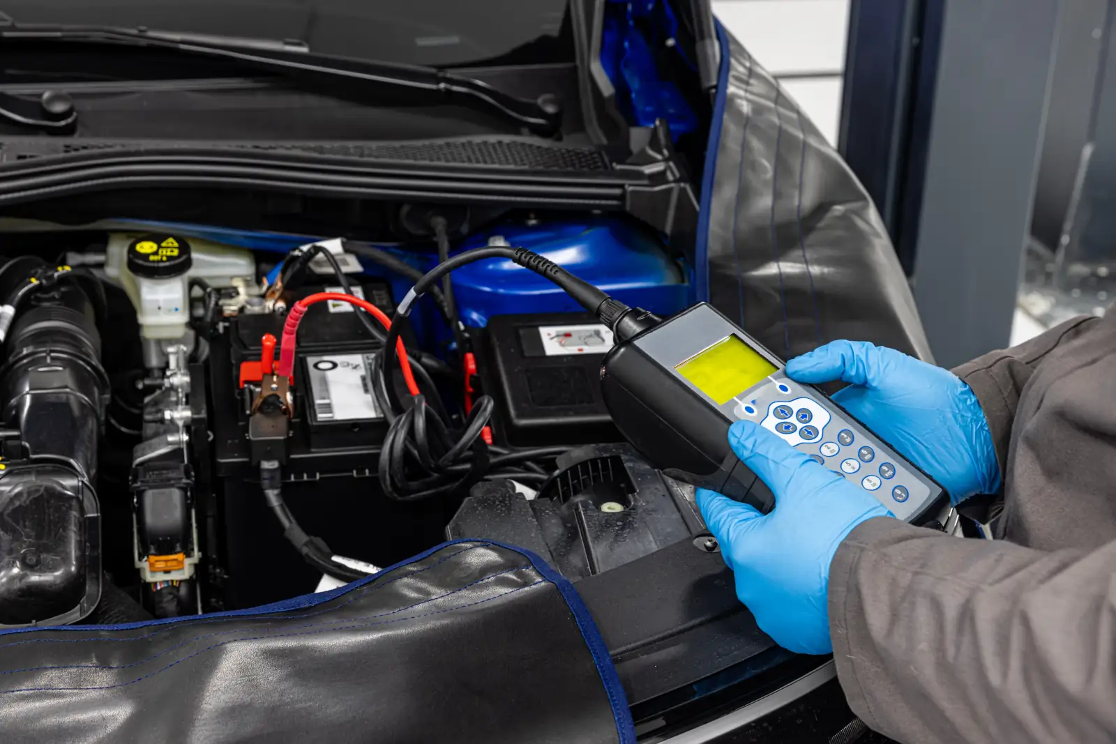 Professional mechanic checking car battery health and charging status with diagnostic equipment