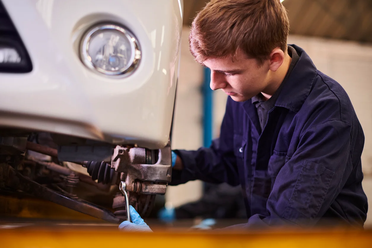 Professional AutoChain mechanic working on car brake system with modern tools and equipment